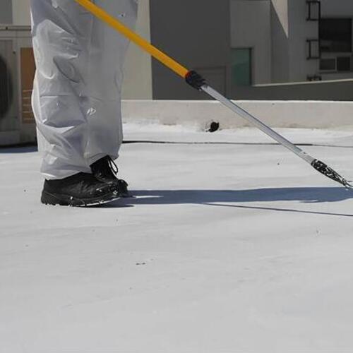 worker applying an acrylic roof coating
