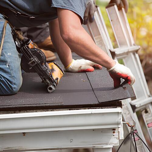 a roofer working on damaged shingles